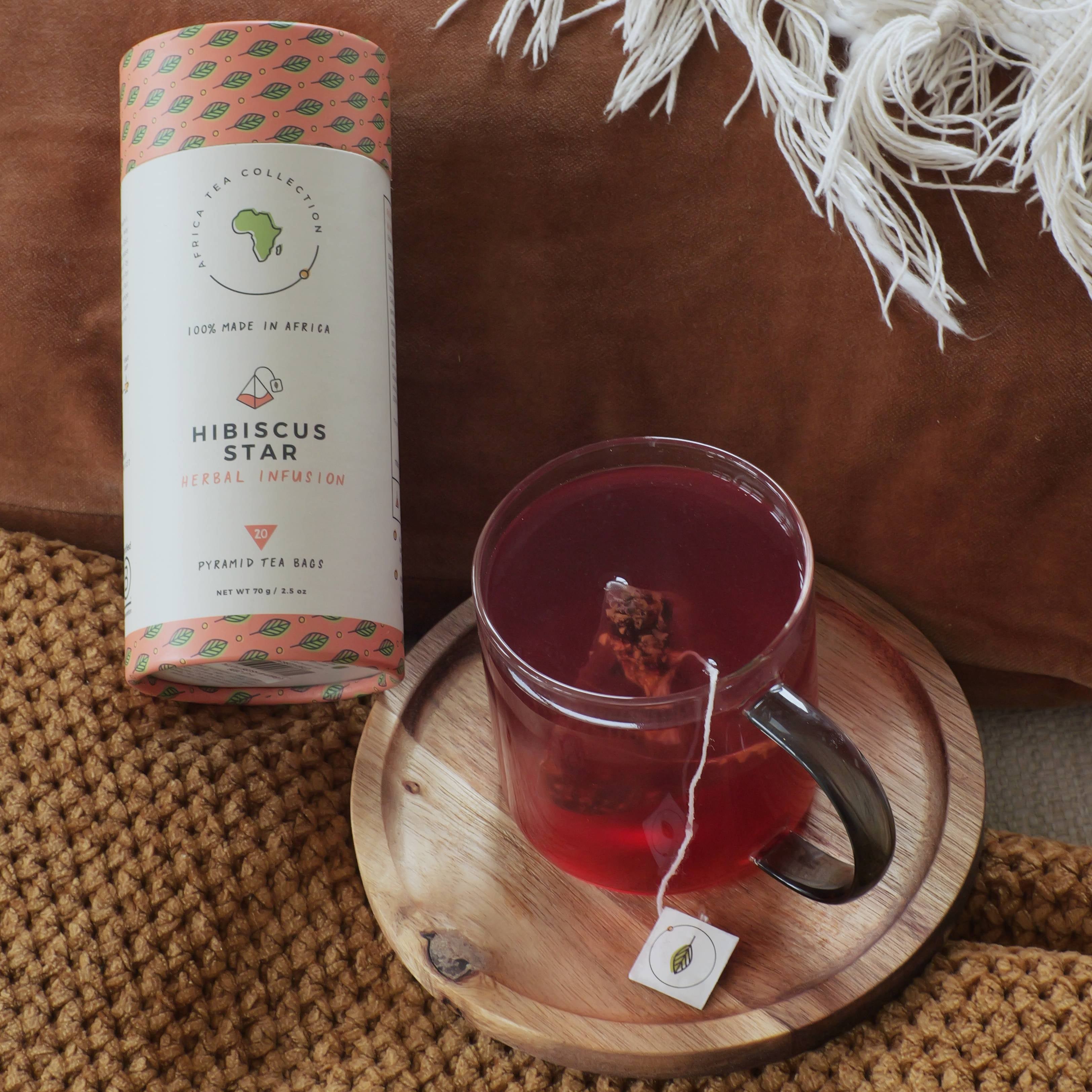 Hibiscus Star tea packaging with a glass of tea on a wooden coaster.