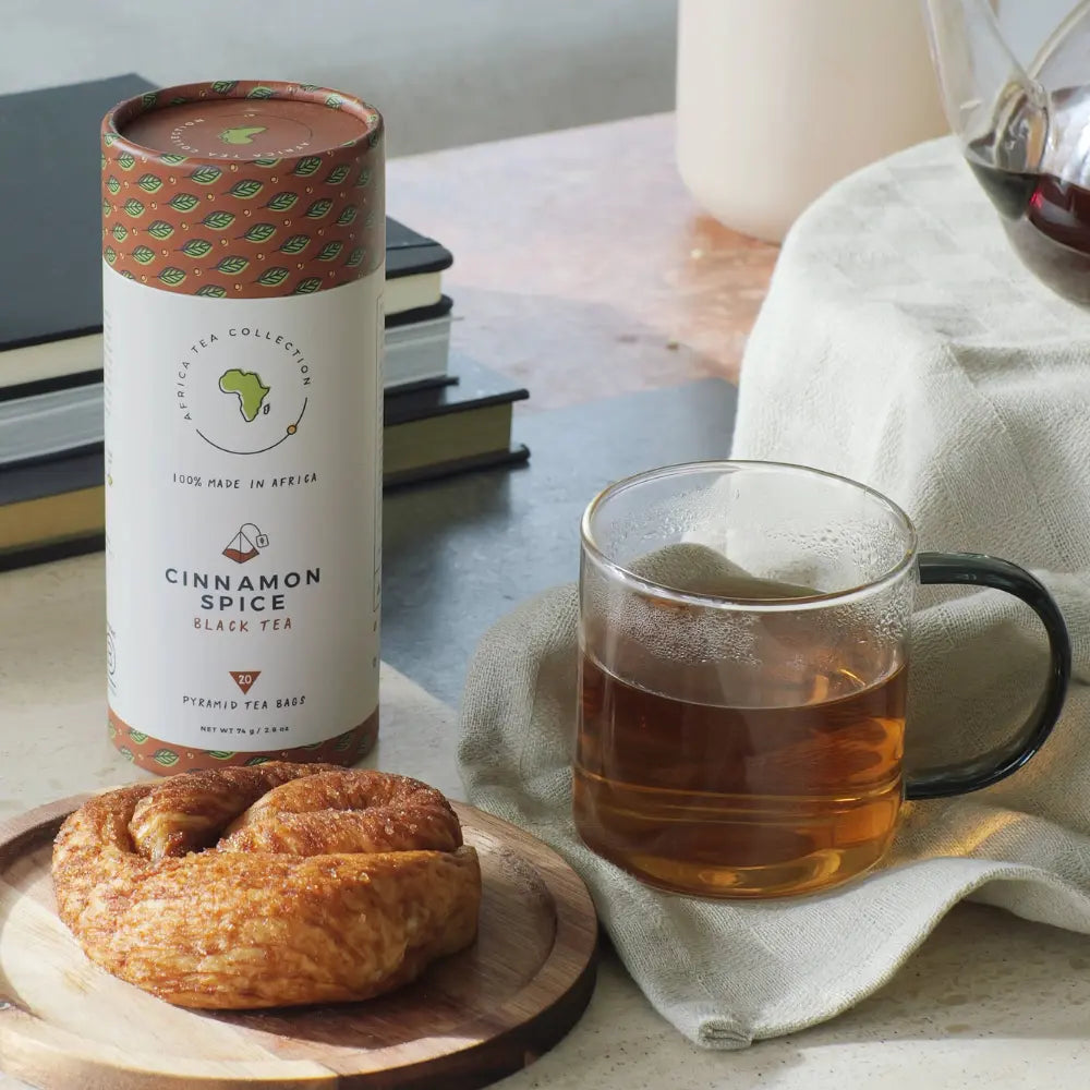 Cinnamon spice black tea canister with a mug of tea and pastry on a table.