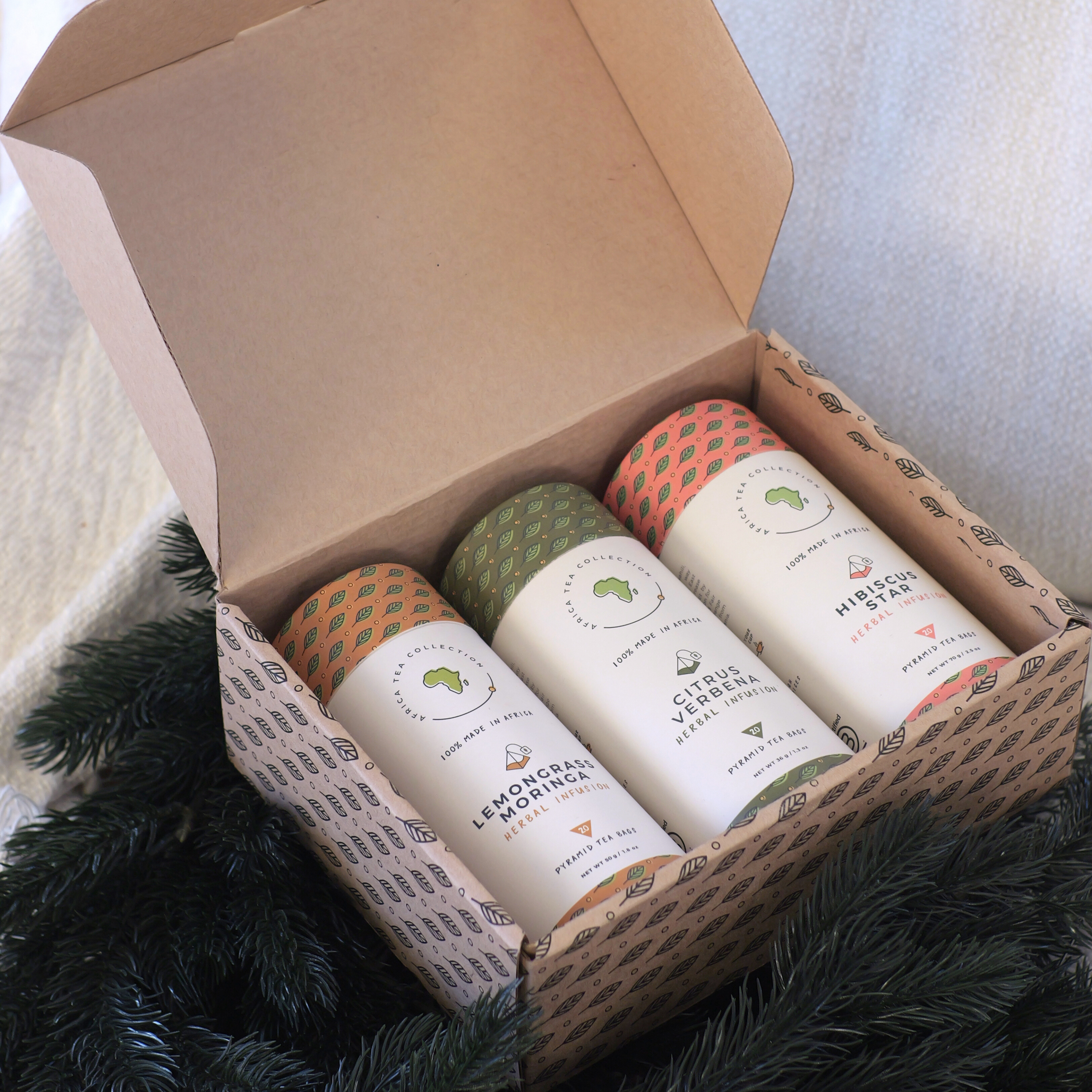 Three tea blends in a cardboard box on a textured surface