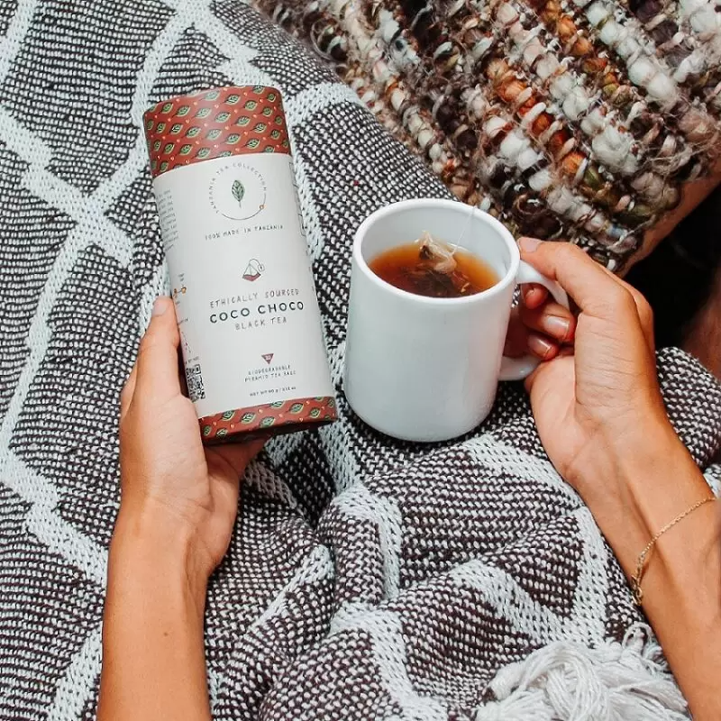 Person holding Coco Choco black tea blend tube and cup