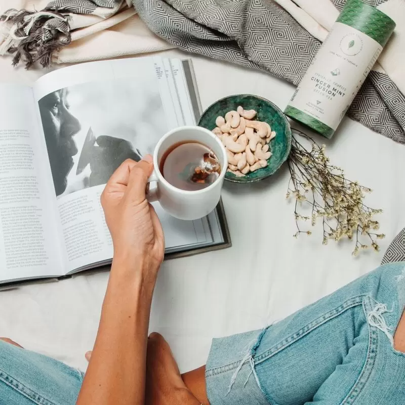 Woman sitting in bed and drinking delicious handcrafted Ginger Mint Fusion tea