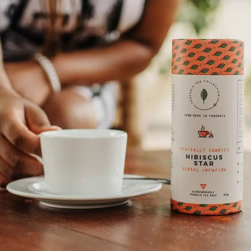 Woman reaching out to tea cup containing Hbiscus Star tea blend