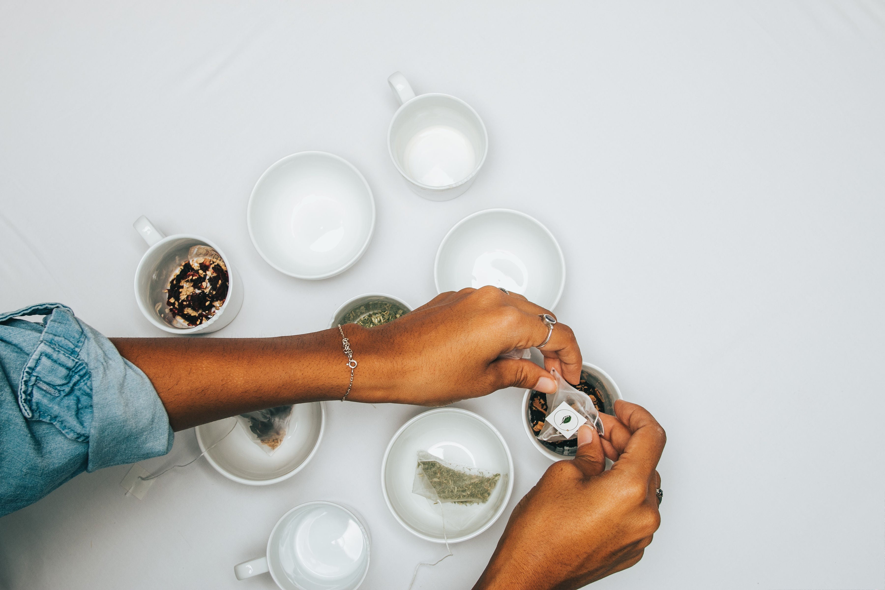 Hand placing pyramid tea bags into cups